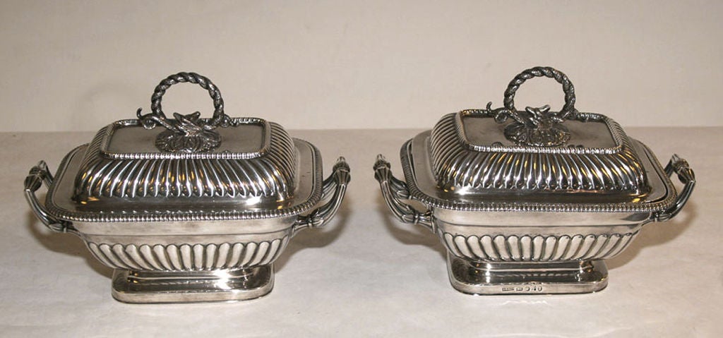 EACH STERLING SILVER SAUCE TUREEN WITH ROUNDED RECTANGULAR TAPERED BODY AND DOMED COVER PARTLY CHASED WITH FLUTES, THE BODY WITH DENTILATED BORDER AND LEAF- CHASED REEDED HANDLES ON A PLAIN ROUNDED RECTANGULAR FOOT, THE COVER WITH DETACHABLE RING